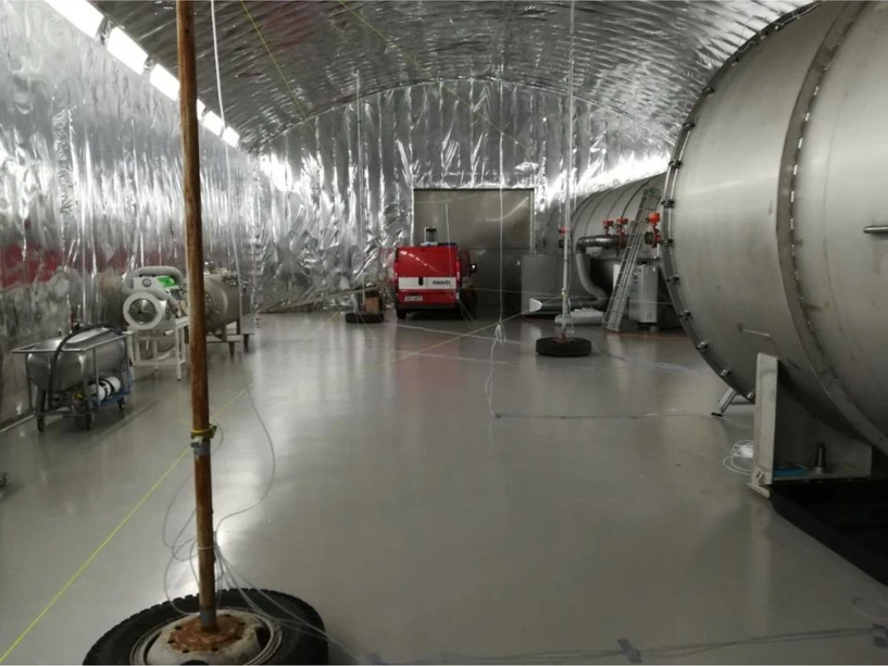 SÚJCHBO: Obrázek 1 - testovací rozložení v hale s rastrem odběrných míst propojených trubičkami. V pozadí Skenovací a zobrazovací systém SIGIS 2 pro dálkovou detekci analytů